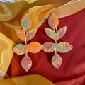 Tiered leaf dangle earrings in orange, muted green, and mauve with gold-colored flecks and connecting rings