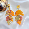 Three-tier autumn leaf earrings in orange, dusty rose, and sage green with gold-colored flecks and gold-tone stud tops