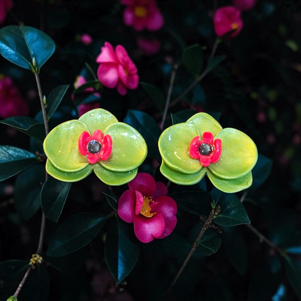 Lime green orchid-inspired polymer clay stud earrings with bright pink centers and a glossy resin finish